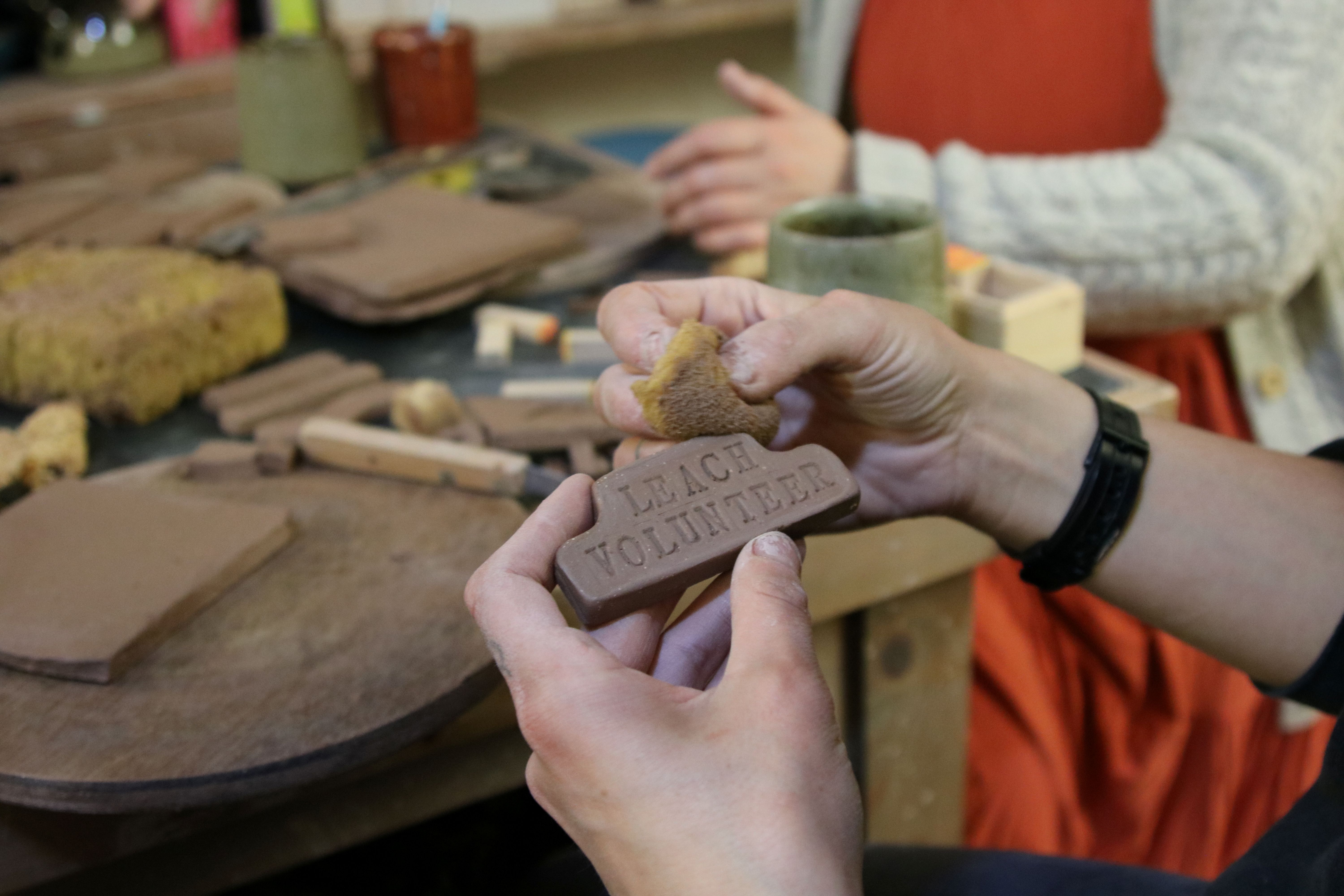 A volunteer makes a badge with clay to wear when volunteering