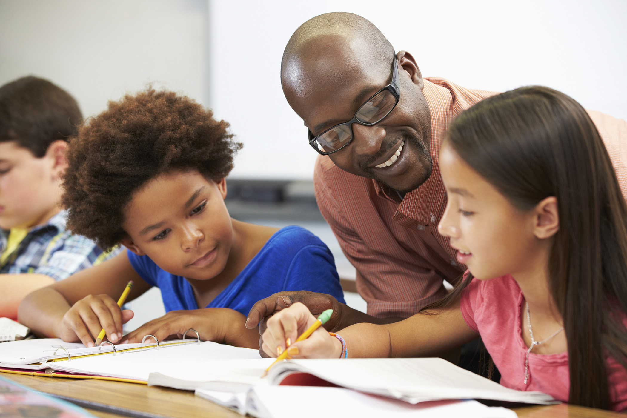 A tutor works with students completing schoolwork 